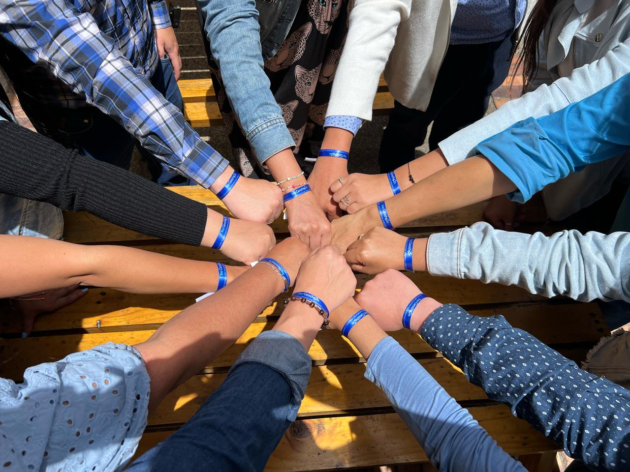 Manos del equipo de Gesthion unidas con las manillas de la marca — cultura de afinidad y trabajo en equipo